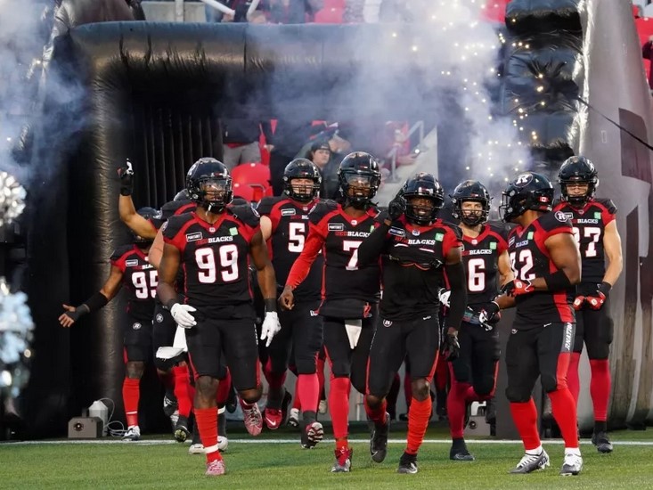 Ottawa Redblacks players running onto the playing field